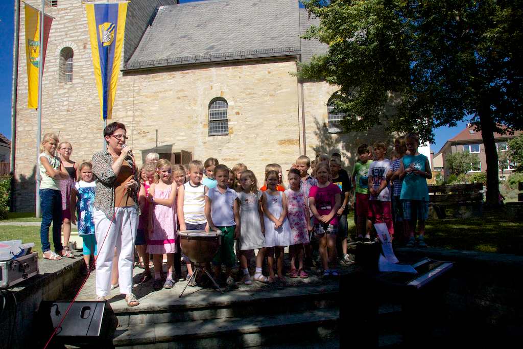 <p>Jungen und Mädchen sangen unter der Leitung von Fr. Hillekötter vor der Alfener Kirche</p>